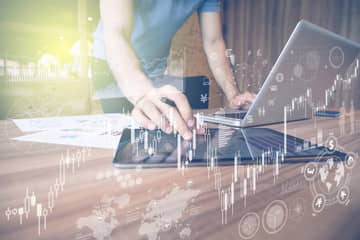 Man standing at desk with hand on mouse and symbols overlaying photo